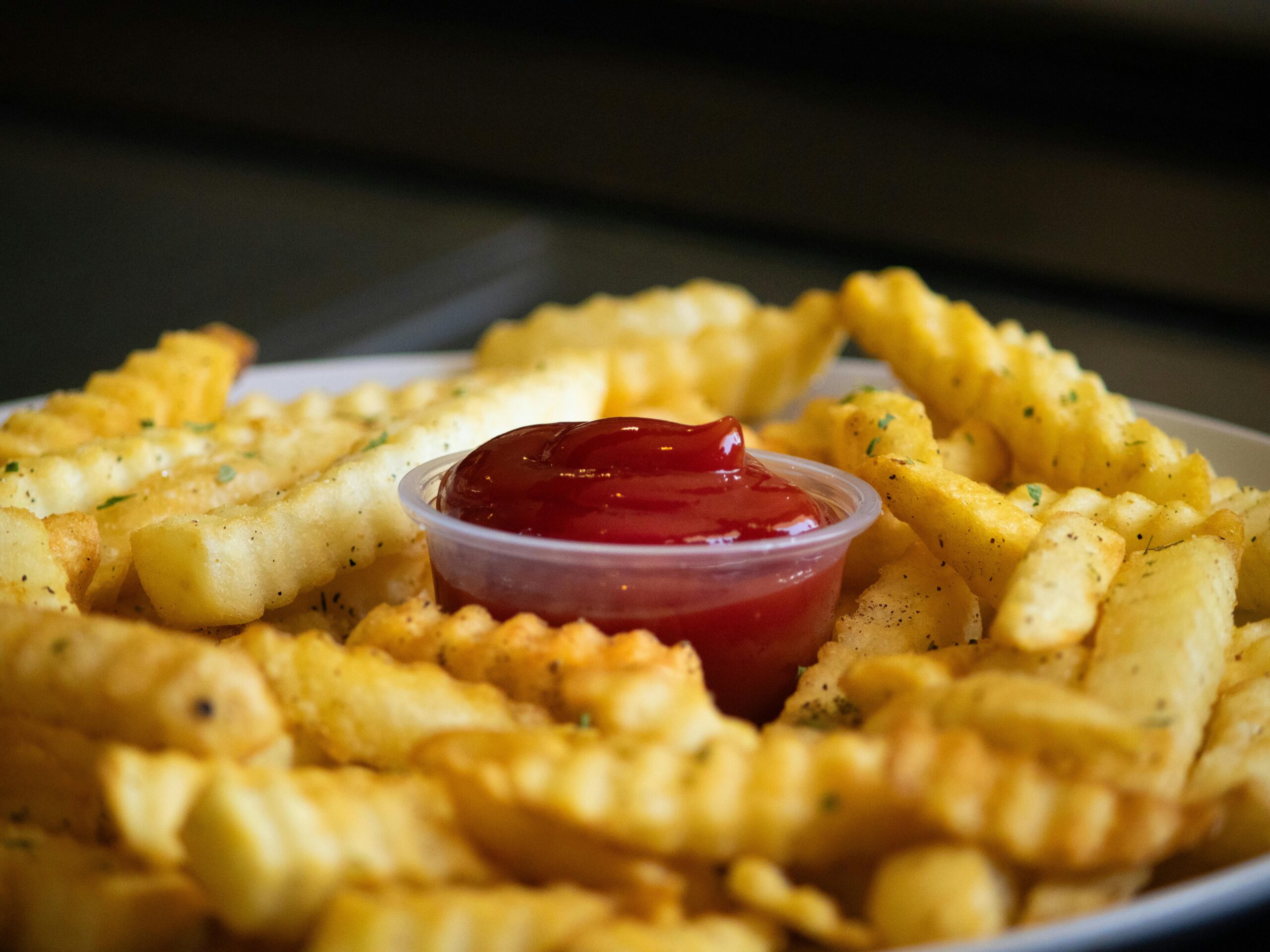 Меню A plate of crispy crinkle-cut French fries with a side of ketchup, perfect for food enthusiasts.